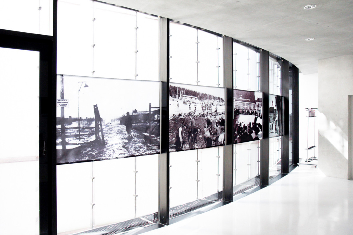Halbtransparente Nachkriegsfotografien vor einer Glasfassade