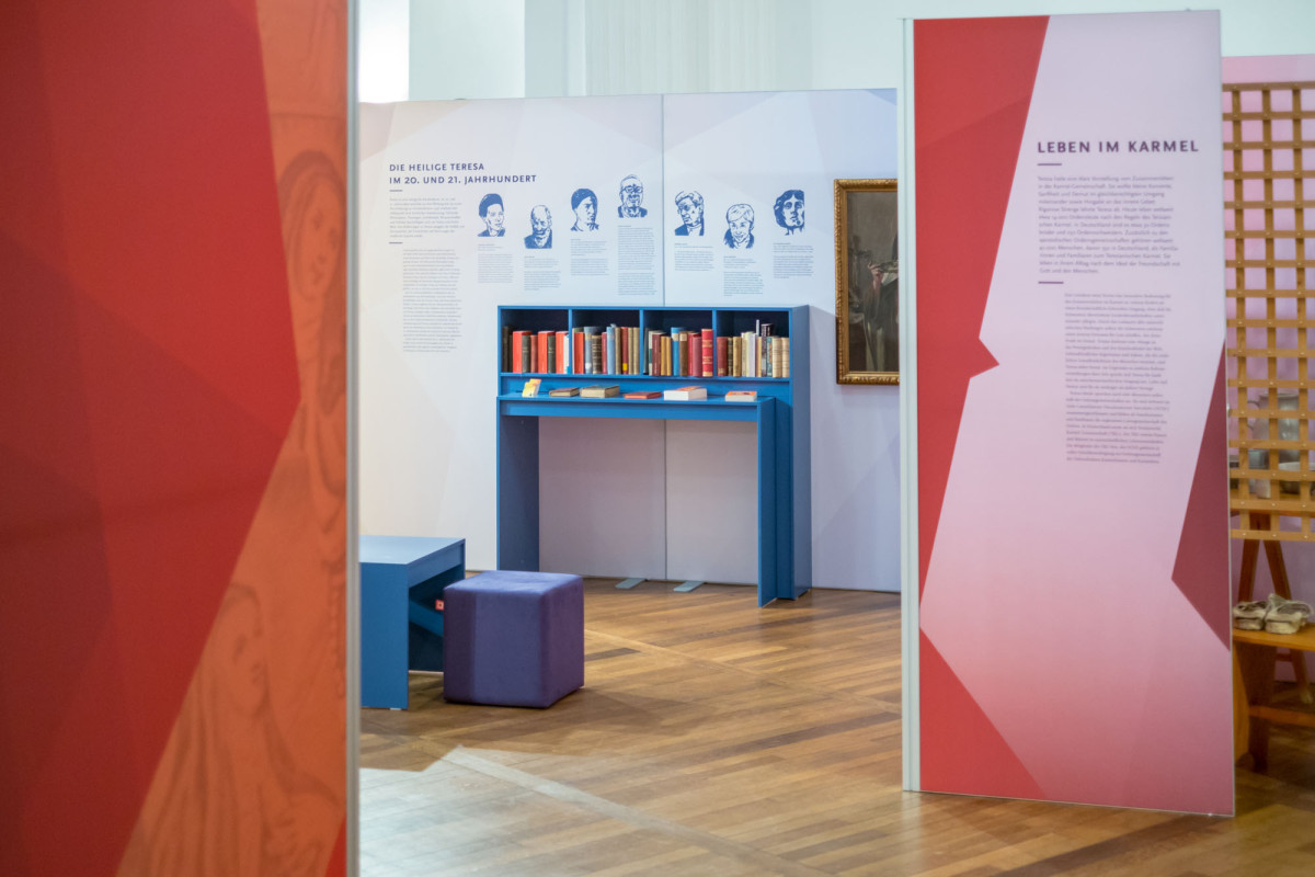 Ausstellungsbereich mit Bibliothek und illustrierten Portraits